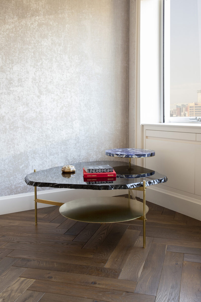 three tiered coffee table with books on it next to a window