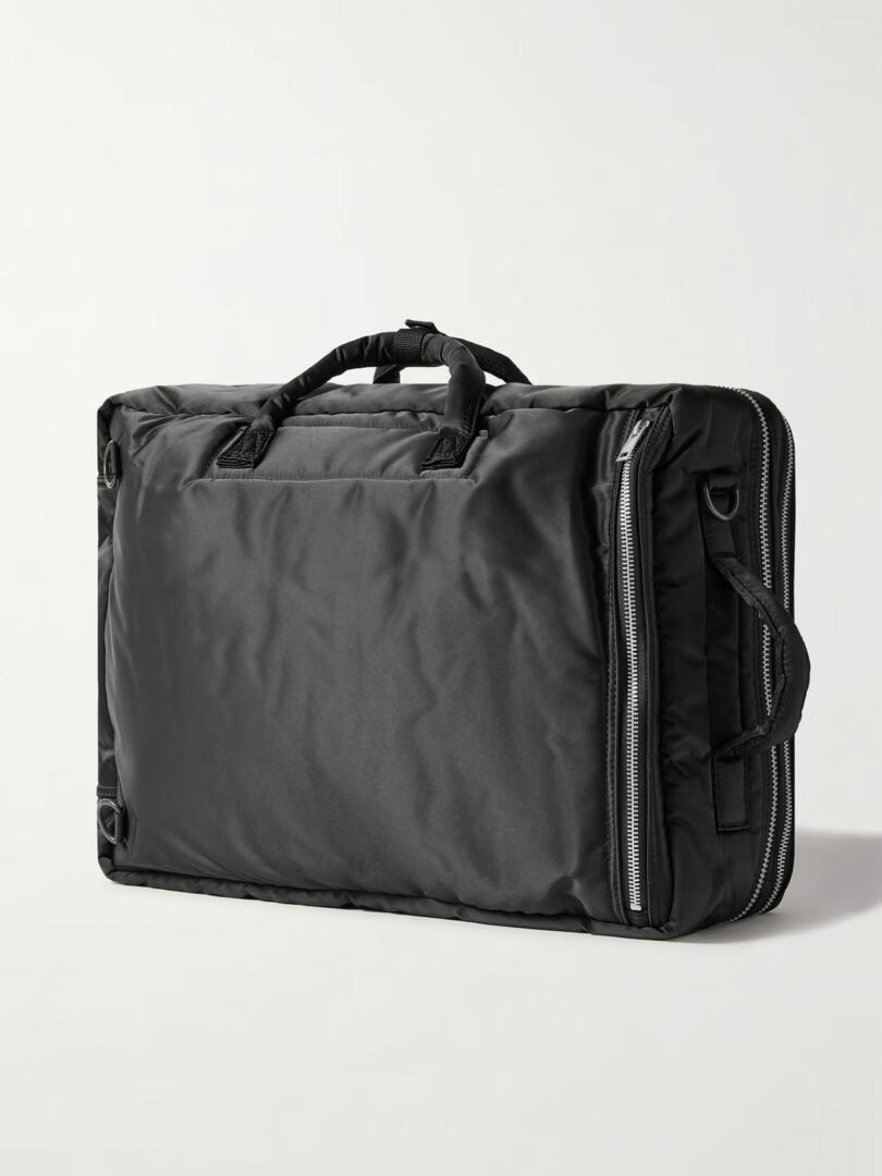 A black nylon duffel bag with silver zippers and handles, elegantly showcasing Richard Parr's signature style, set against a plain background.