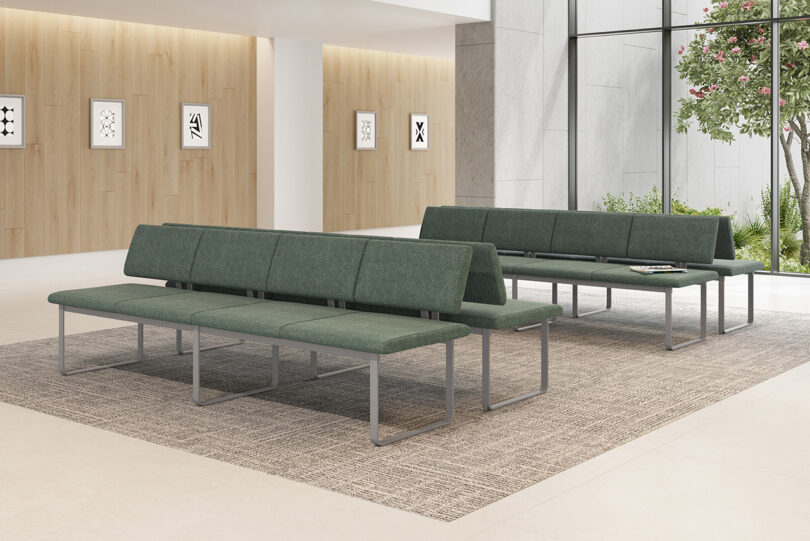 Modern office lobby with green upholstered modular benches, wooden wall panels, and a flowering pink tree in a minimalist style.