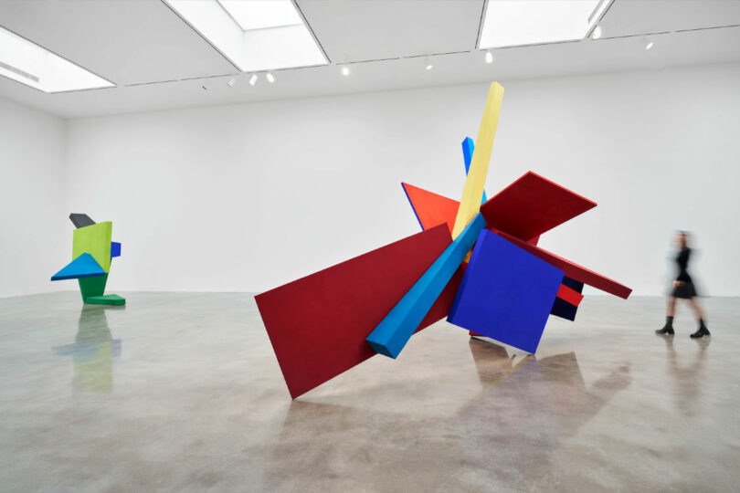 Woman approaches 2 large geometric sculptures