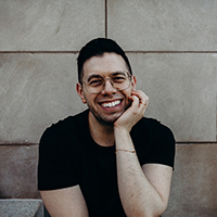 small headshot of man in black t-shirt with hand under chin