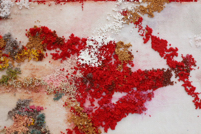 White brushstroke over thousands of red beads