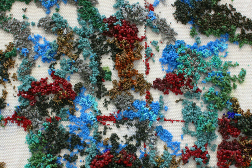 Thousands of blue, red and green beads in highly textural clumps.