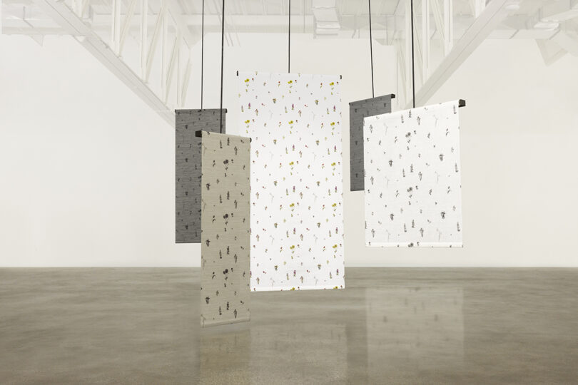 Hanging textile panels in a gallery space with light reflecting off the polished floor.