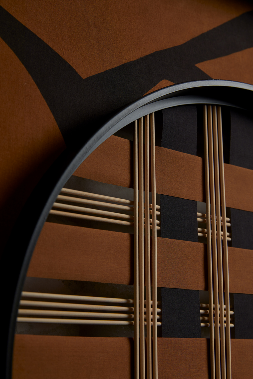 A close-up of an abstract design with black lines and brown, rectangular elements, intersected by thin, vertical metal rods