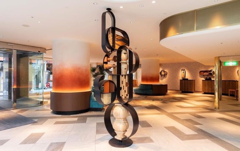 modern hotel lobby with contemporary art sculptures, a spacious layout, and minimalist furniture arranged around the reception area.