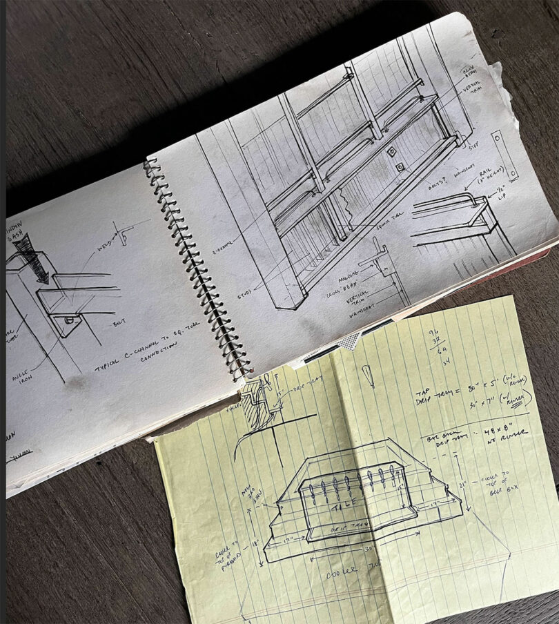 Two open notebooks sit on a table, one showcasing Chuck Cerankosky's detailed architectural sketches and the other featuring technical drawings on yellow paper