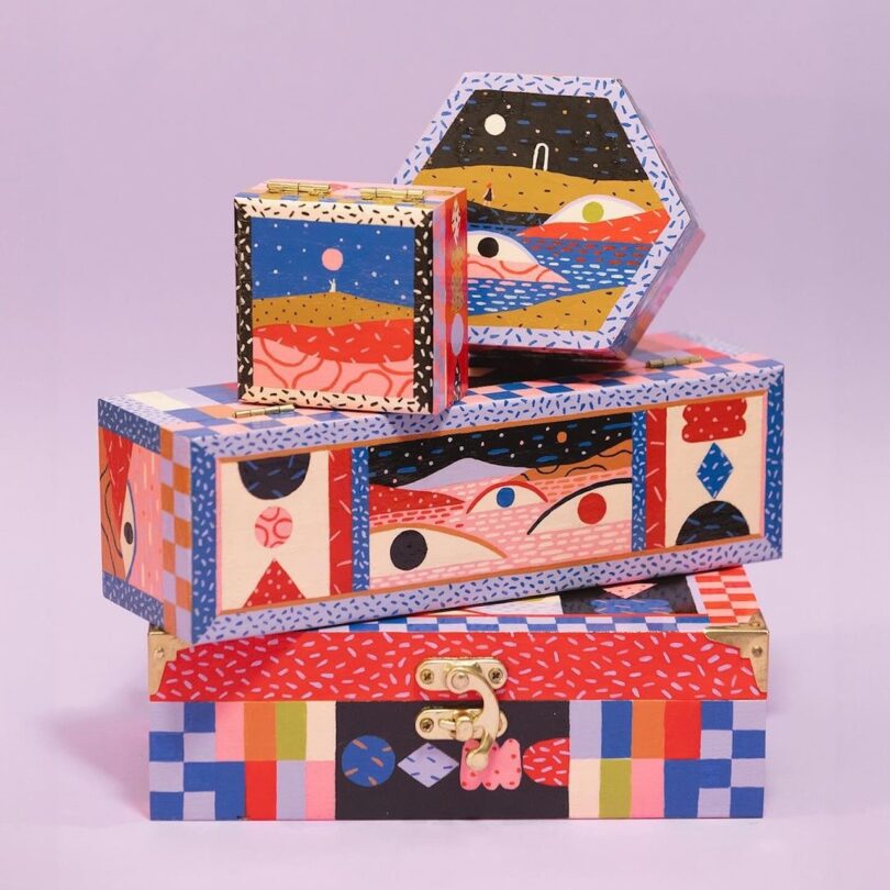 Three colorful, intricately patterned boxes of varying shapes and sizes stacked on top of each other against a plain background